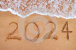 Happy New Year 2024 concept, lettering on the beach. Written text on the sea beach at sunrise