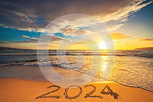 Happy New Year 2024 concept, lettering on the beach. Written text on the sea beach at sunrise