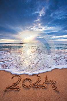 Happy New Year 2024 concept, lettering on the beach. Written text on the sea beach at sunrise