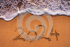 Happy New Year 2024 concept, lettering on the beach. Written text on the sea beach at sunrise