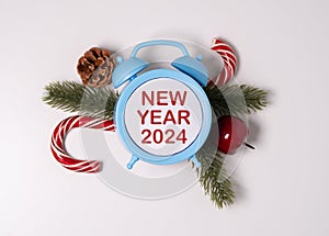 Happy New Year 2024 text on alarm clocks with New Year\'s paraphernalia.