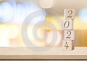 Happy New Year 2024 on wood cube block and blur abstract bokeh light with copy space background, Happy new year 2024 greeting card