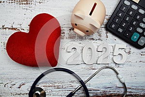 Happy New Year 2025 for healthcare and medical with piggy bank, stethoscope and calculator on wooden background
