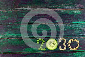 Happy New Year 2030 number made of fruits and berries and vvegetavles on green wooden background