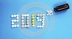 Happy New Year banner for medical theme. Number 2019 made by colored pills/tablets spilling out of brown glass bottle on blue back