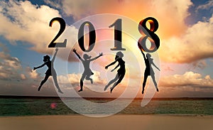 Happy new year card 2018. Silhouette women jumping on tropical beach over the sea and 2018 number with sunset background