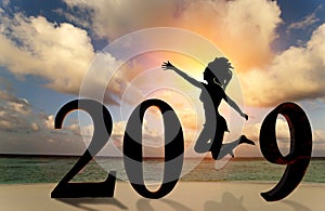 Happy new year card 2019. Silhouette young woman jumping on tropical beach over the sea and 2019 number with sunset background