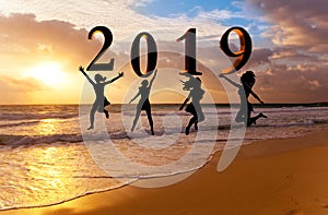 Happy new year card 2019. Silhouette young woman jumping on tropical beach over the sea and 2019 number with sunset background