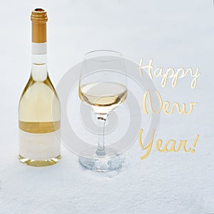 Happy New Year card. Bottle and glass of white wine chilled by snow.