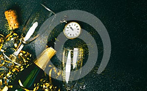 Happy New Year. Champagne bottle with two glasses,golden streamers,sparkling glitter and antique clock with copy space. New Years