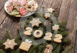 Happy New Year, Christmas cookies decorating evergreen branches on wooden background