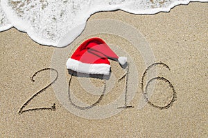 Happy new year 2016 with christmas hat on sandy beach