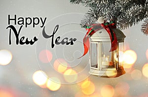 Happy New Year. Christmas lantern with candle hanging on fir tree branch against light background
