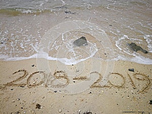 Happy new year concept, 2018 to 2019 written in the sand on a beach