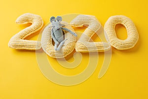 Happy New year concept. 2020 knitted yallow numbers with the symbol of the year the rat on a yellow background. Seasonal funny