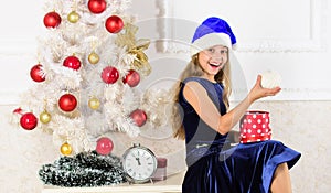 Happy new year concept. Child celebrate christmas at home. Kid girl sit near christmas tree hold gift box. Little girl
