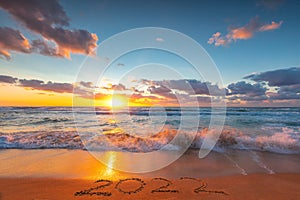 Happy New Year 2022 concept on the sea beach sand ; ocean sunrise