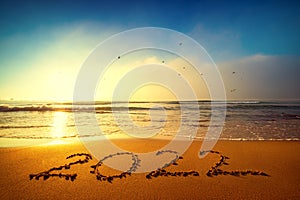 Happy New Year 2022 concept, lettering on the beach. Written text on the sea beach at sunrise