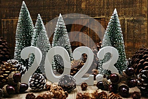 Happy New year 2023 decoration with Christmas tree and pine cones on wooden background