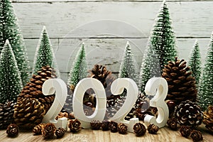 Happy New year 2023 decoration with Christmas tree and pine cones on wooden background