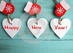 Happy New Year.Decorative white wooden Christmas hearts and red mittens on blue wooden background.Winter holidays concept.