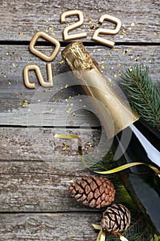Happy New Year 2022! Flat lay composition with bottle of sparkling wine on wooden table