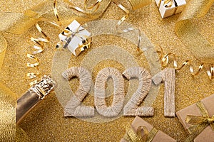 Happy New Year. Gold background with 2021 lettering, craft gifts, champagne bottle and christmas tinsel