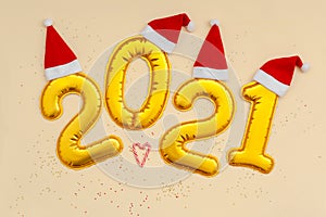 Happy New Year Golden digits 2021 numbers with christmas hat on beige background with confetti