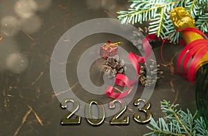 Happy new year 2023 greeting card on a brutal metal background with a branch of a Christmas tree, bright lights and a bottle of