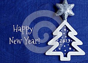 Happy New Year greeting card.White christmas tree with 2019 number on a dark blue wooden background.