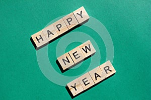 Happy New Year greeting words are laid out in wooden letters on a green background
