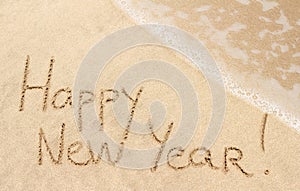 Happy New Year handwritten on sand