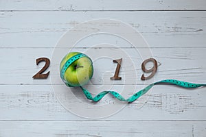 2019 Happy New Year for healthcare, Wellness and medical concept. green apple, measuring tape and wooden number