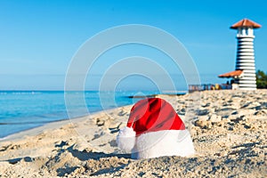 Happy New Year holidays at Sea. Santa hat on sandy beach - christmas holiday concept