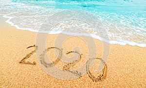 Happy New Year 2020, lettering on the beach with wave and  blue sea. Numbers 2020 year on the sea shore, New Years concept