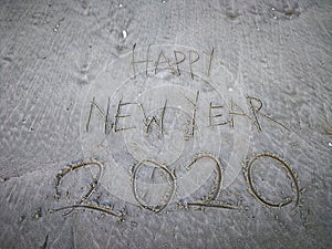 Happy new year 2020, lettering on the beach with wave and clear blue sea. Numbers 2020 year on the sea shore.