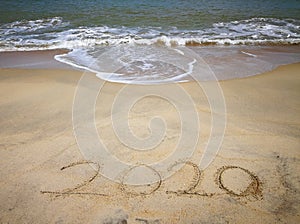 Happy new year 2020,lettering on the beach with wave and clear blue sea. Numbers 2020 year on the sea shore. Beautiful beach.