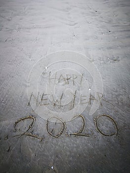 Happy new year 2020, lettering on the beach with wave and clear blue sea. Numbers 2020 year on the sea shore.