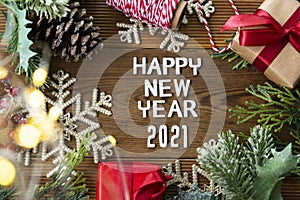 Happy New Year letters with red gift boxes, fir branches and Christmas decoration over wooden background. Top view