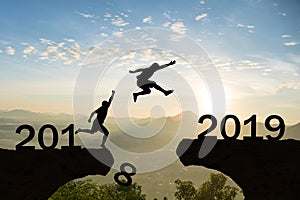 Happy New Year 2019 Men jump over silhouette mountains