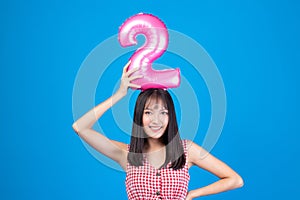 Happy new year and Merry Christmas concept. Beautiful young asian woman with balloons number 2 on blue background