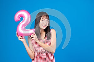 Happy new year and Merry Christmas concept. Beautiful young asian woman with balloons number 2 on blue background