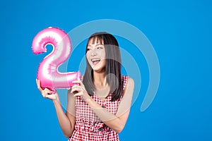 Happy new year and Merry Christmas concept. Beautiful young asian woman with balloons number 2 on blue background