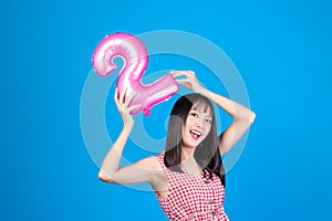 Happy new year and Merry Christmas concept. Beautiful young asian woman with balloons number 2 on blue background