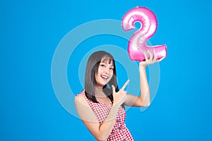 Happy new year and Merry Christmas concept. Beautiful young asian woman with balloons number 2 on blue background