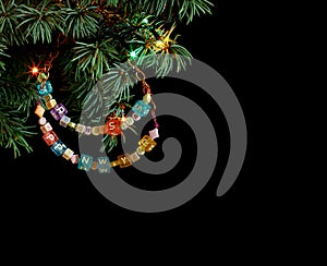 Happy New Year and Merry Christmas hand made craft colorful beaded letter garland on Christmas tree branch