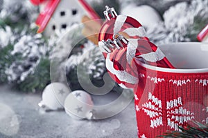 Happy New Year or Merry Christmas. Striped candy sticks in red cup on backgrounds cozy houses wrapped, Christmas tree branches in