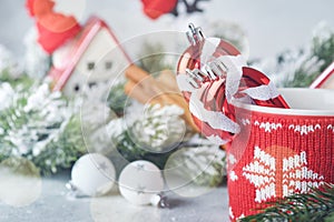 Happy New Year or Merry Christmas. Striped candy sticks in red cup on backgrounds cozy houses wrapped, Christmas tree branches in