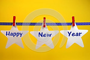 Happy New Year message greeting written across white stars and red pegs on blue polka dot ribbon hanging from pegs on a line