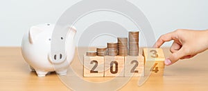 Happy New Year with piggy bank and flipping 2023 change to 2024 block. Resolution, Goals, Plan, Action, Money Saving, Retirement